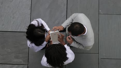 Three-people-standing-on-street-and-looking-at-tablet